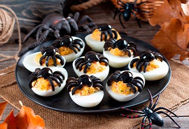 Huevos arácnidos sobre un plato negro para una fiesta de Halloween.