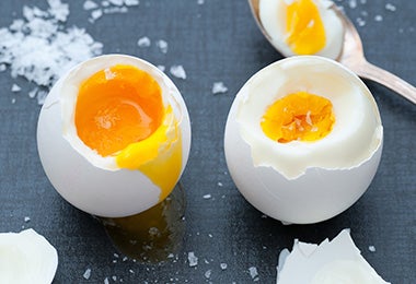 : Dos huevos hervidos, uno con la yema líquida y el otro con la yema dura.