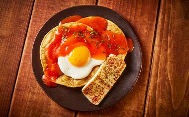 Un desayuno con huevo, tortillas y salsa.