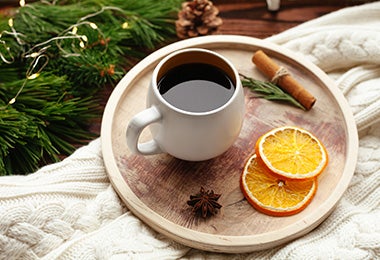 Dos rodajas deshidratadas de naranja, junto a un café.