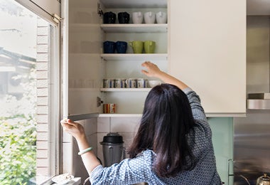  Mujer ordenando su alacena con tazas y vasos