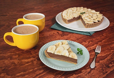 Porción de pie de chocolate con cambur con dos tazas de chocolate