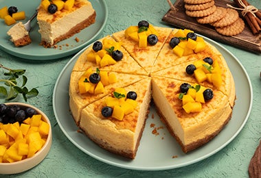 Un pie de mango con base de galletas y decorado con frutas.