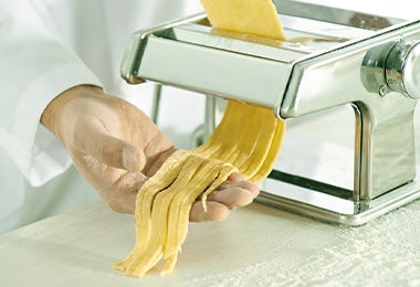 Persona corta fideos yakisoba con máquina procesadora de pasta