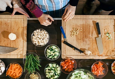 Tabla de corte con cuchillos y vegetales cortados 