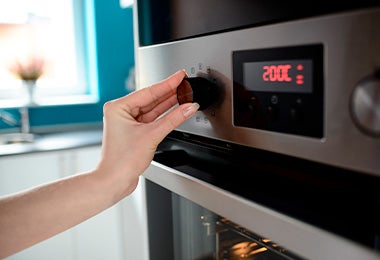 Mujer graduando la temperatura de su horno para calentar waffles