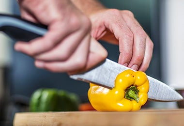 Una persona cortando un pimentón con un cuchillo, un utensilio clave para un asado