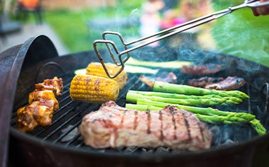 Asado de carne y vegetales, con pinzas para darles vuelta, un utensilio muy importante.