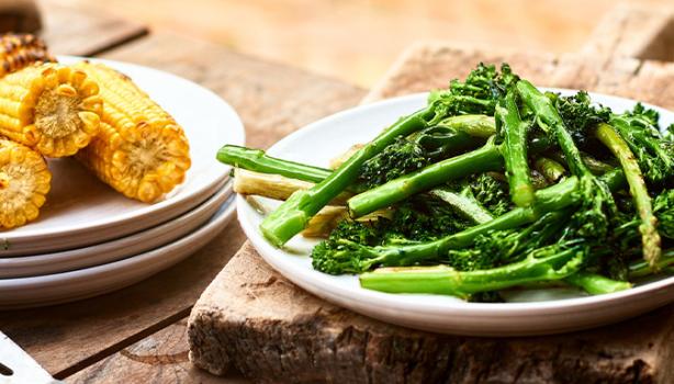 Mazorcas y espárragos sobre una mesa de madera en un asado vegetariano