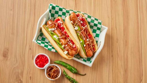 Plato con hot dogs, cebollas caramelizadas, tomates y ajíes 