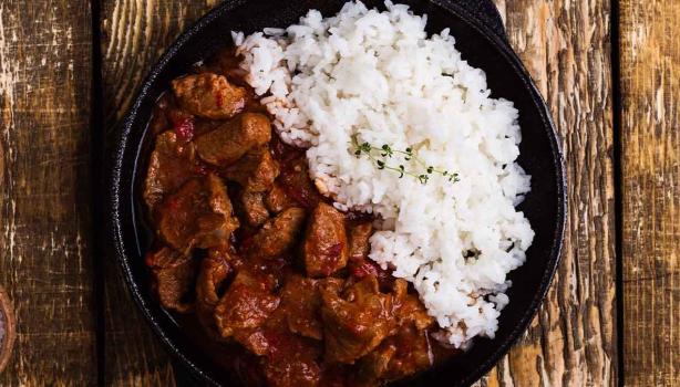 Carne en cuadros y arroz blanco en un sartén de hierro.