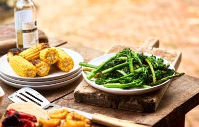 Mazorcas y espárragos en un asado vegetariano Mazorcas y espárragos sobre una mesa de madera en un asado vegetariano