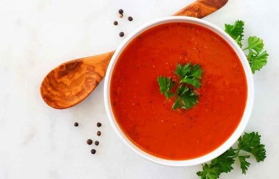 Crema de tomate con perejil, una de las recetas más famosas, servida con una cuchara de madera. Crema de tomate con perejil, una de las recetas más famosas, servida con una cuchara de madera.