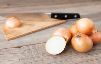 Cebollas sobre una mesa, listas para cortar en julianas o rodajas Cebollas sobre una mesa, listas para cortar en julianas o rodajas