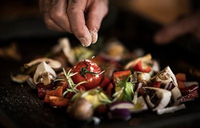 Si unas verduras quedan muy saladas se pueden limpiar con agua fría. Una persona usando sal para sazonar unas verduras.