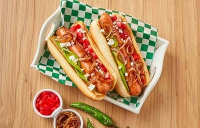 Plato con hot dogs, cebollas caramelizadas, tomates y ajíes 