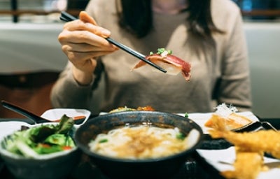 El éxito de la comida japonesa promueve el turismo gastronómico. Mujer comiendo en Japón, un gran destino del turismo gastronómico.