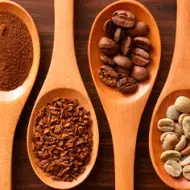 Cucharones de madera con café en polvo y grano
