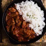 Carne en cuadros y arroz blanco en un sartén de hierro.
