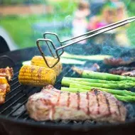 Asado de carne y vegetales, con pinzas para darles vuelta, un utensilio muy importante.